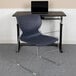 A blue Flash Furniture Hercules stacking chair with a gray sled base next to a desk with a laptop on it.