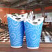 Two blue LK Packaging paper cups on a table.