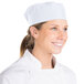 A woman wearing a white Chef Revival baker's skull cap with a mesh top.