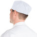 A man wearing a white Chef Revival baker's skull cap.