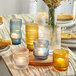 A table with a group of Acopa glass vases filled with flowers and candles.