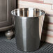 A polished stainless steel Focus Hospitality wastebasket on a carpet.