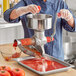 A person in gloves using a Tre Spade manual tomato mill to process tomatoes.