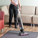 A person using a Hoover ONEPWR Evolve Pet cordless vacuum on a carpet.