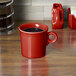 A Fiesta Scarlet china mug with a handle on a wooden surface.