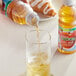 A hand pouring Tropicana Apple Juice from a plastic bottle into a glass.