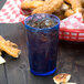 A blue Cambro plastic tumbler filled with ice on a table with a basket of pretzels.