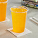 A plastic cup with orange Gatorade and ice on a table.