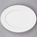 A white Tuxton oval china platter with a swirl rim.
