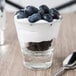 A Libbey Endeavor shot glass filled with yogurt and blueberries with a spoon on the table.