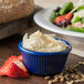 A Carlisle cobalt blue fluted ramekin filled with cheese and strawberries next to a salad.