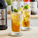 A glass of Lotus Plant Energy unsweetened ice tea with lemon slices and mint leaves on a table.