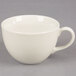 A Tuxton Venice eggshell white china cup with a handle on a gray surface.