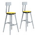 A pair of National Public Seating Titan lab stools with yellow high-pressure laminate seats and backrests.