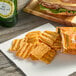 A bag of Sun Chips Harvest Cheddar on a napkin next to a sandwich.