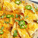 A plate of nachos topped with Violife Just Like Cheddar vegan cheese and jalapenos.