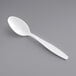 A Visions white plastic teaspoon on a gray surface.