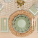 A table setting with a Sophistiplate Sage Scalloped Edge Paper Guest Towel, white plate, and green cutlery.