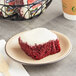 An Individually wrapped Ne-Mo's Bakery red velvet cake square on a plate.