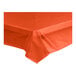 A tangerine plastic tablecloth on a table in an outdoor catering setup.