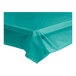 A teal plastic table cover unrolled on a table.