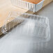 A clear plastic dome lid on a table over a foil bread loaf pan.