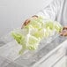 A person holding a Cambro clear polycarbonate drain tray of lettuce.