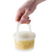 A hand holding a GET clear plastic soup container with food.
