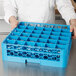 A chef using a Carlisle glass rack extender to hold many glasses in a blue tray.