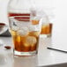 A Libbey Gibraltar rocks glass with ice and amber liquid on a table.