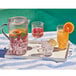 A tray with Sophistiplate clear plastic tumblers filled with fruit juice and ice, and a pitcher of fruit juice.