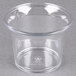 A Carlisle clear plastic sauce cup on a gray surface.