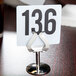 A Tablecraft stainless steel menu holder with a white card and black numbers on it.