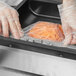 A person in gloves using a Chamber Vacuum Packaging Bag to store carrots in a food container.