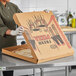 A person wearing gloves holding a Choice kraft corrugated pizza box with a pizza inside.