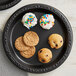 A group of cookies on a black Ecopax polypropylene plate.
