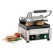 A Waring Panini Sandwich Grill with two sandwiches cooking on it.