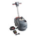 A NaceCare Solutions walk behind floor scrubber with a battery.