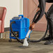 A person using a NaceCare carpet spot extractor to clean a carpet.