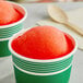 A red and green cup with a round ball of red Philadelphia Water Ice in it.