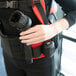 A person wearing a body harness using a NaceCare backpack vacuum with a black ASTB5 Free Flo Kit brush.
