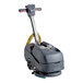 A grey NaceCare Solutions walk behind floor scrubber with a handle and wheels.