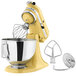 A KitchenAid Artisan stand mixer in yellow with bowl attached.