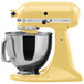 A KitchenAid Majestic Yellow mixer with a bowl and a whisk attachment.