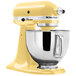 A close up of a yellow KitchenAid Artisan stand mixer with a bowl.