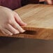 A person's hand holding a Choice wood cutting board.