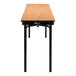 A National Public Seating Bannister Oak Plywood folding table with T-Mold edge and black legs.