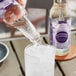 A hand pouring Reading Soda Works Blueberry Lavender soda into a glass of ice.
