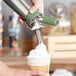 A hand using an iSi stainless steel tulip decorating tip to make a frozen yogurt.