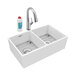 A white Elkay double bowl farmhouse sink with a silver faucet and soap dispenser.